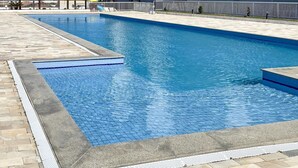 Una piscina rettangolare con bordo piastrellato, circondata da un solarium in pietra.