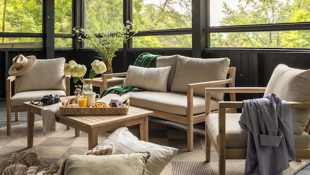 A cozy outdoor seating area with wooden furniture, a woven mat, and a table with a basket and flowers. - Three Bears Cottage: Cozy Wears Valley Cottage (Sevierville)