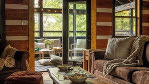 A cozy cabin interior with a wooden interior, a dining area with a table and chairs, and a view of the outdoors through a door. - Three Bears Cottage: Cozy Wears Valley Cottage (Sevierville)