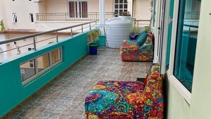 Un balcon doté d’un sol carrelé, d’un climatiseur blanc et de fauteuils en forme de sacs de couchage aux couleurs vives.