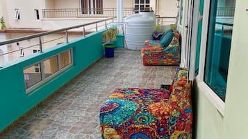 A balcony with tiled flooring, a white air conditioning unit, and colorful bean bag chairs.