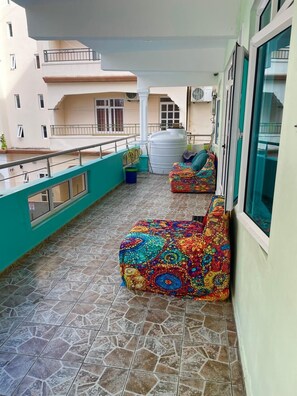 A balcony with tiled flooring, a white air conditioning unit, and colorful bean bag chairs. - Charming 2-bedroom apartment with AC, WiFi in Flic en Flac (Flic en Flac)