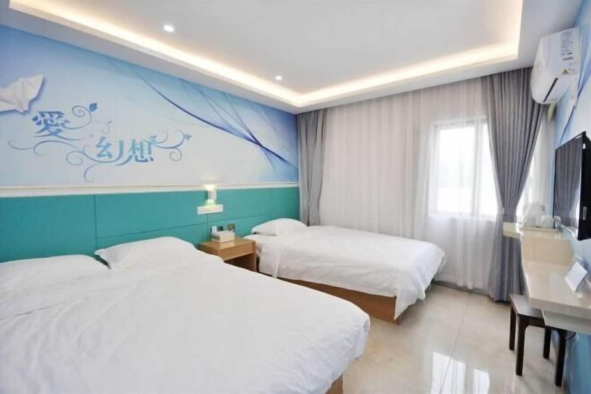 A hotel room with two beds, a desk, a chair, a TV, and a window with curtains.
