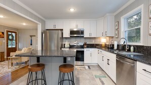 A modern kitchen with white cabinets, stainless steel appliances, and a granite countertop. - Cozy & Tasteful 3Br Cottage Walkable to Downtown (Franklin)