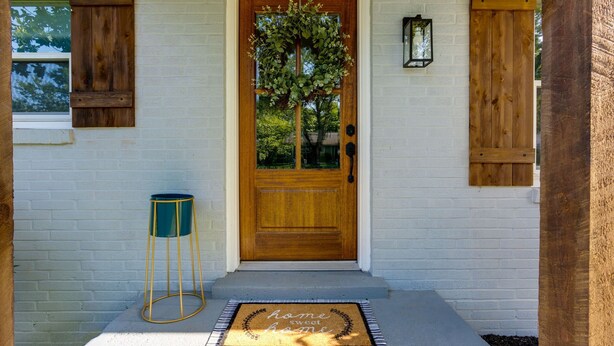 A wooden front door with a glass panel, a doormat with "home sweet home" text, and a small green stool to the left. - Cozy & Tasteful 3Br Cottage Walkable to Downtown (Franklin)