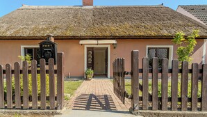 A traditional thatched-roof house with a wooden gate and a sign reading "POST".
