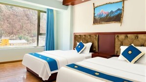 Ein Hotelzimmer mit zwei Betten, einem großen Fenster mit Blick auf Bäume und einem Berg Gemälde an der Wand.