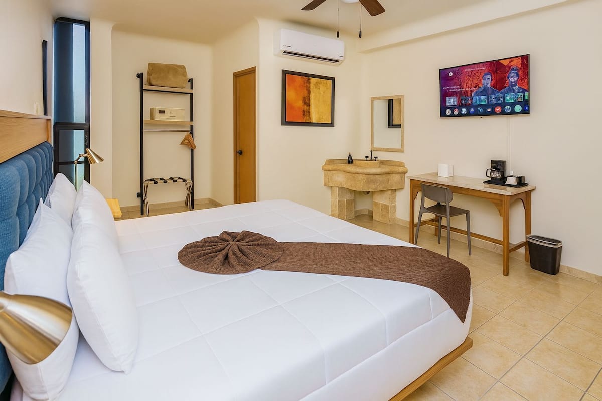 Une chambre d’hôtel équipée d’un lit, d’un bureau, d’une chaise, d’un lavabo et d’une télévision.