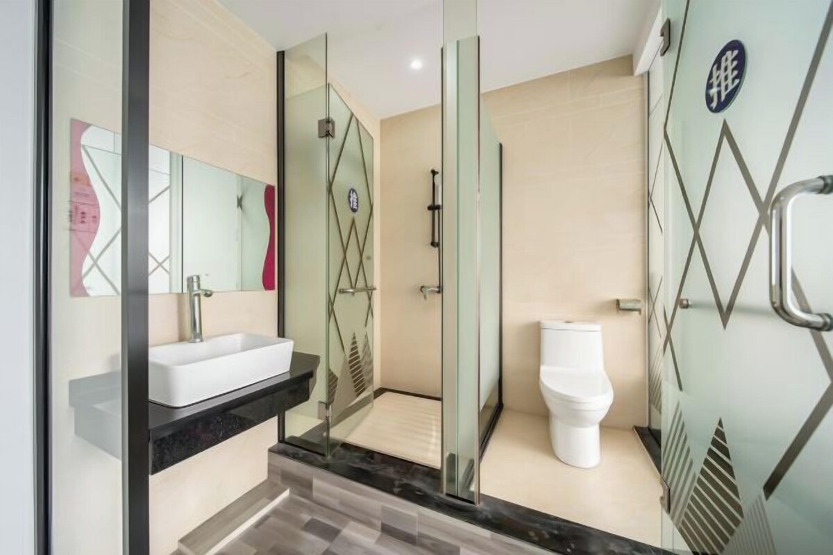 A modern bathroom with a glass-enclosed shower, a white toilet, and a sink with a black countertop.