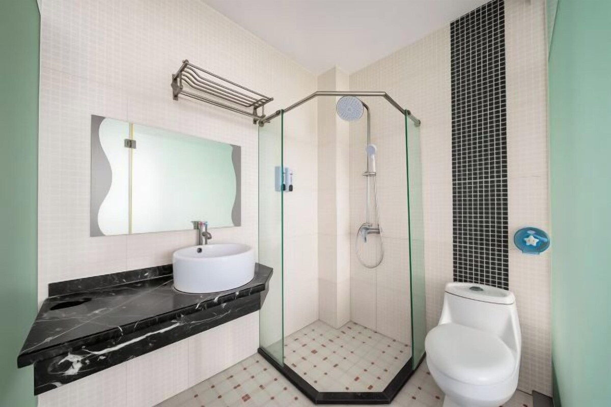 A bathroom with a glass-enclosed shower, a white sink, and a toilet.