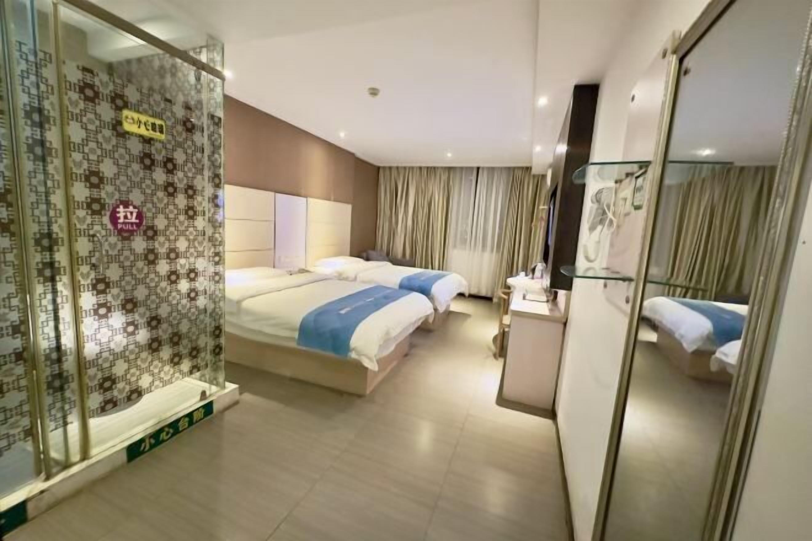 A hotel room with a large bed, a bedside table, a mirror, and a patterned wall.