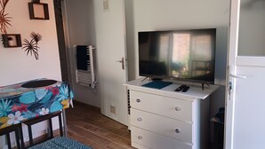 A bedroom with a bed, a TV on a dresser, a window, and a door.