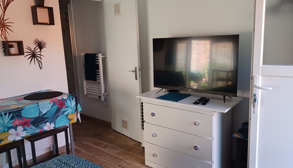 A bedroom with a bed, a TV on a dresser, a window, and a door.