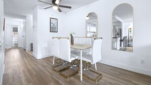 A dining area with a white table and chairs, a ceiling fan, and a large mirror. - Stylish Suite at Stampede w/ Free Parking, AC (Calgary)