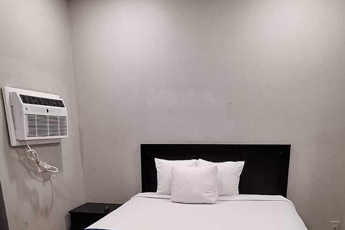 Una camera da letto con un letto, un condizionatore d'aria a parete e un pavimento in legno.