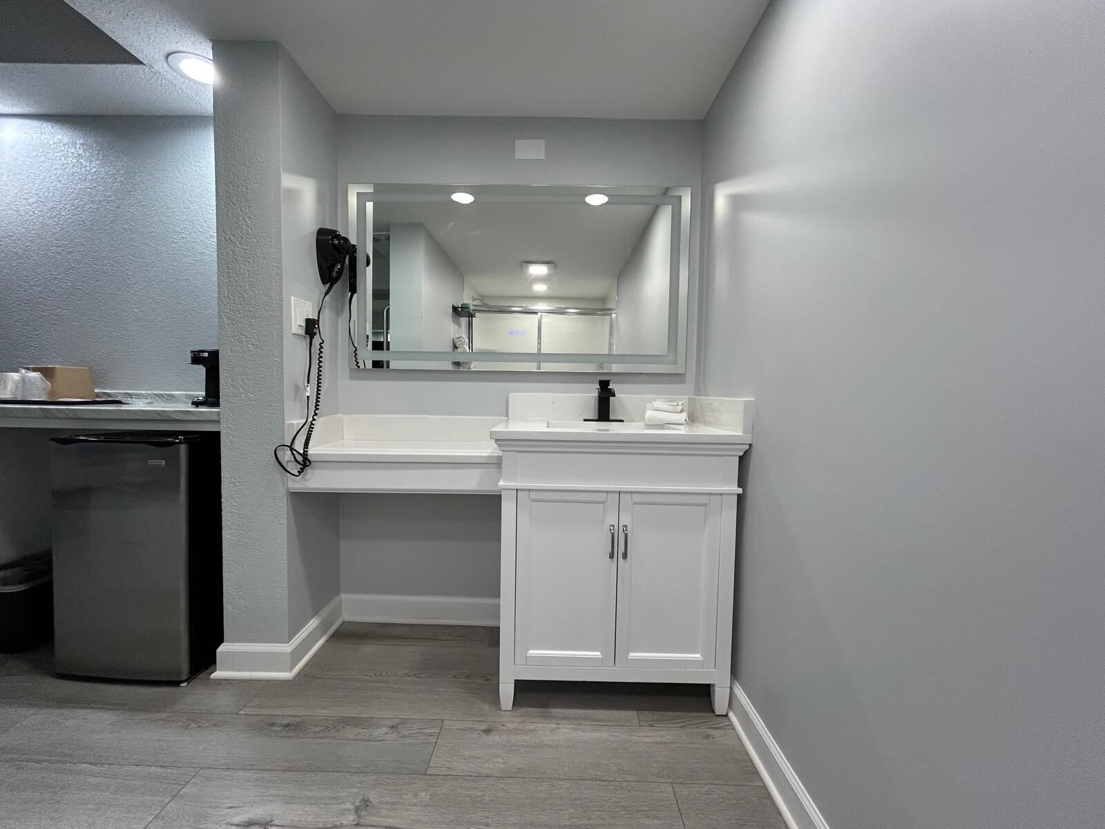 Un baño moderno con tocador blanco, un espejo y lavamanos integrado.