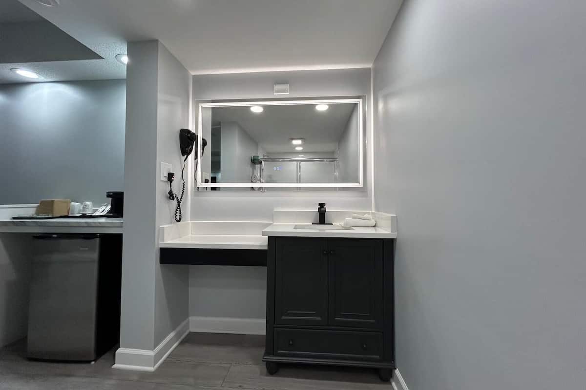 Un bagno moderno con uno specchio grande, un lavandino e un mobile.