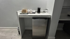 Une petite cuisine équipée comprenant un réfrigérateur intégré, une machine à caf é et un petit plan de travail.