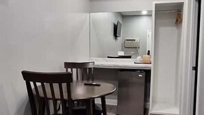 Une cuisine compacte comprenant une table et des chaises, un four encastré et un réfrigérateur.