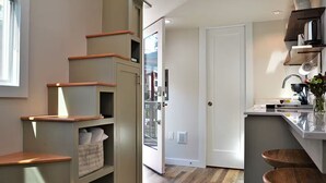 Een moderne keuken met een ingebouwde kookplaat, houten planken en een witte deur naar een andere kamer.