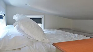 Een slaapkamer met een bed, een raam en een houten bankje.
