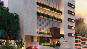 Ein modernes Gebäude mit vertikaler Bepflanzung an der Fassade, einem gut sichtbaren Eingang und einem roten Auto sowie dem Schriftzug "SYRENA" an der Seite.