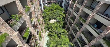 A multi-level residential building with balconies, outdoor seating, and lush greenery.