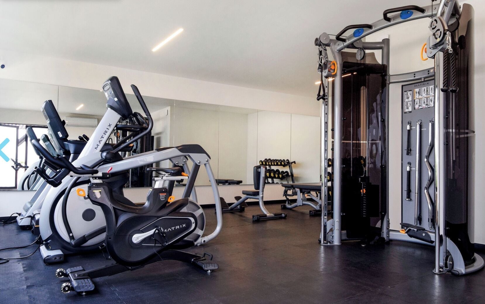 Un gimnasio con equipo cardiovascular, máquinas de pesas y una estructura para sentadillas.