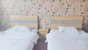 Deux lits simples avec des têtes de lit en bois, une literie blanche et une petite table de chevet en bois placée entre les deux.
