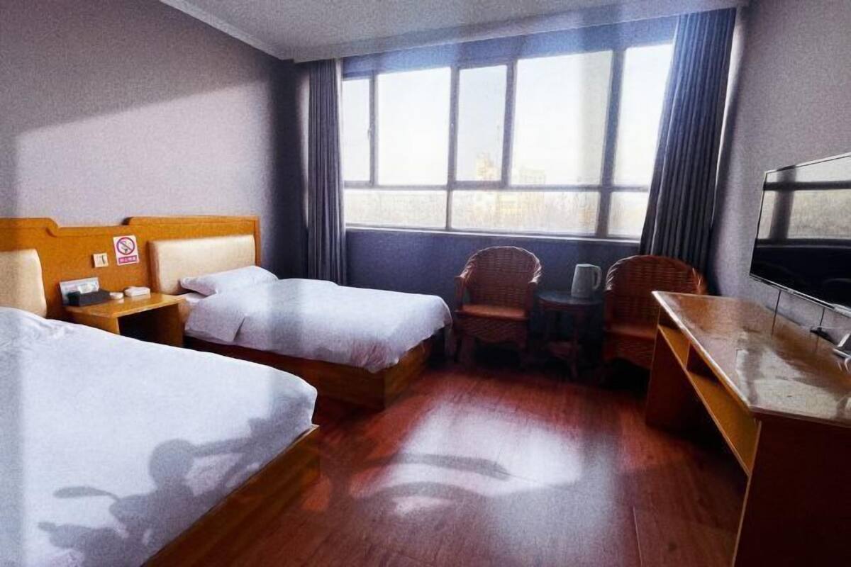 Una camera d'albergo con due letti, una scrivania, una sedia e un televisore.