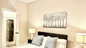 A bedroom with a bed, two nightstands, a wall art piece, and a door with a storage unit. - 3-bedroom #1738 townhome in Cleveland—central air, ceiling fans, WiFi, cable. (Cleveland)