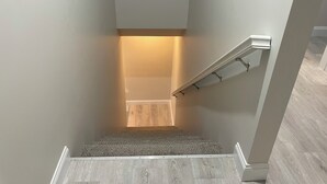 A modern staircase with a light-colored wall and a wooden floor. - 3-bedroom #1738 townhome in Cleveland—central air, ceiling fans, WiFi, cable. (Cleveland)