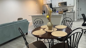 A modern kitchen with white cabinets, a built-in microwave, and a dining area with a round table and chairs. - 3-bedroom #1738 townhome in Cleveland—central air, ceiling fans, WiFi, cable. (Cleveland)