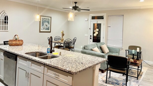 A modern kitchen with a granite countertop, a dishwasher, and a dining area with a table and chairs. - 3-bedroom #1738 townhome in Cleveland—central air, ceiling fans, WiFi, cable. (Cleveland)