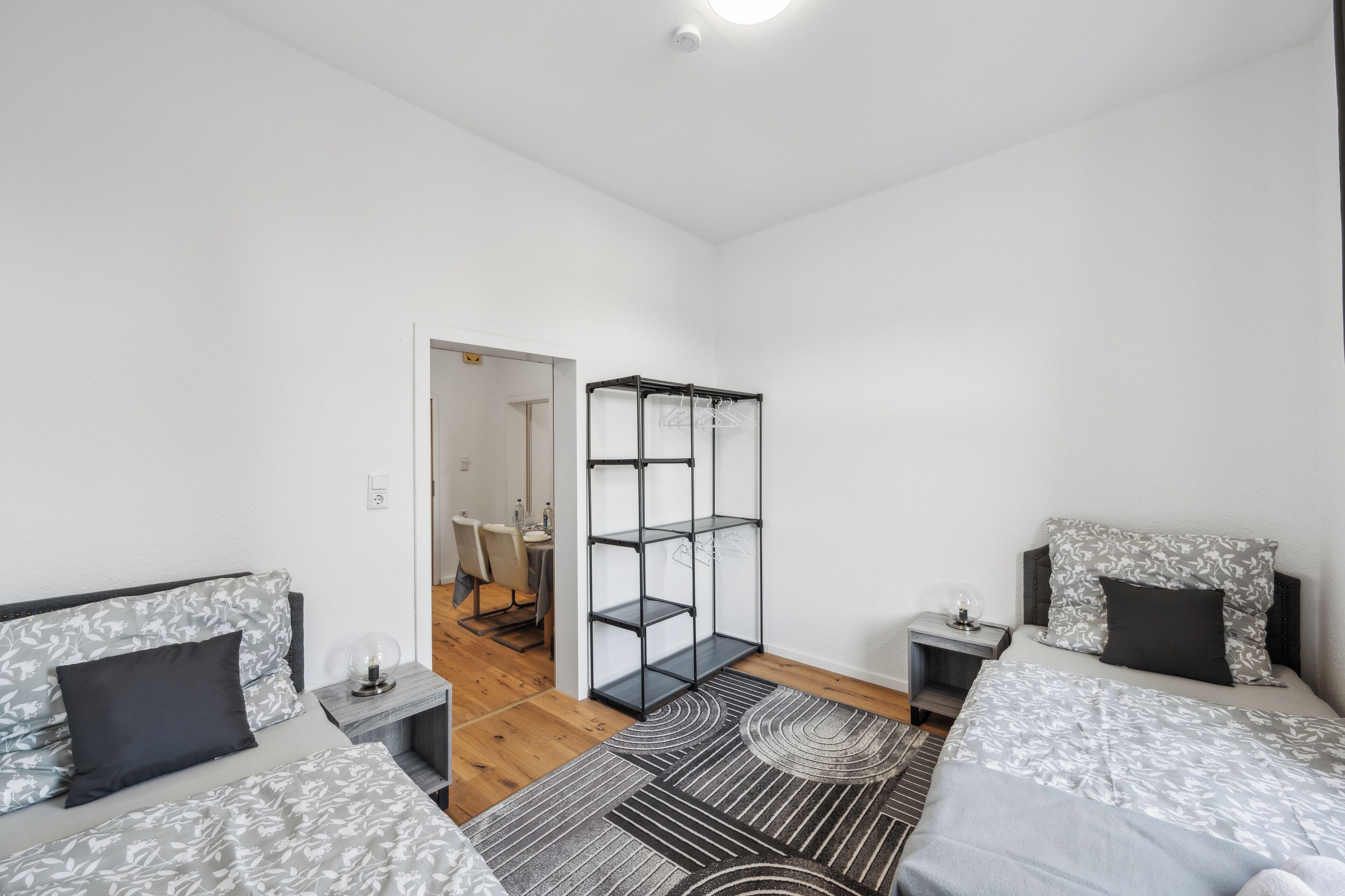 Une chambre moderne avec deux lits, une armoire et un petit espace bureau.