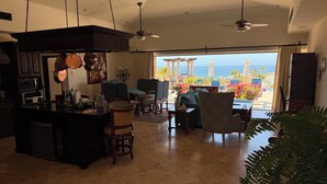 A spacious living area with a kitchen, dining area, and a balcony with a view of the ocean. - 3-bedroom, 5-bathroom Luxury Villa at the Residences in Hacienda Encantada (Cabo San Lucas)