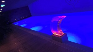 A swimming pool with a blue-lit water feature and a logo on the wall. - E1 18th Floor Studios - Scenic Sea & Beach Views (Gibraltar)