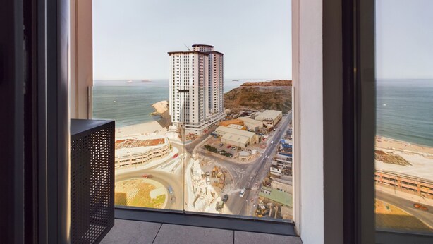 A high-rise building with a view of a coastal cityscape, including a beach and a highway. - E1 18th Floor Studios - Scenic Sea & Beach Views (Gibraltar)