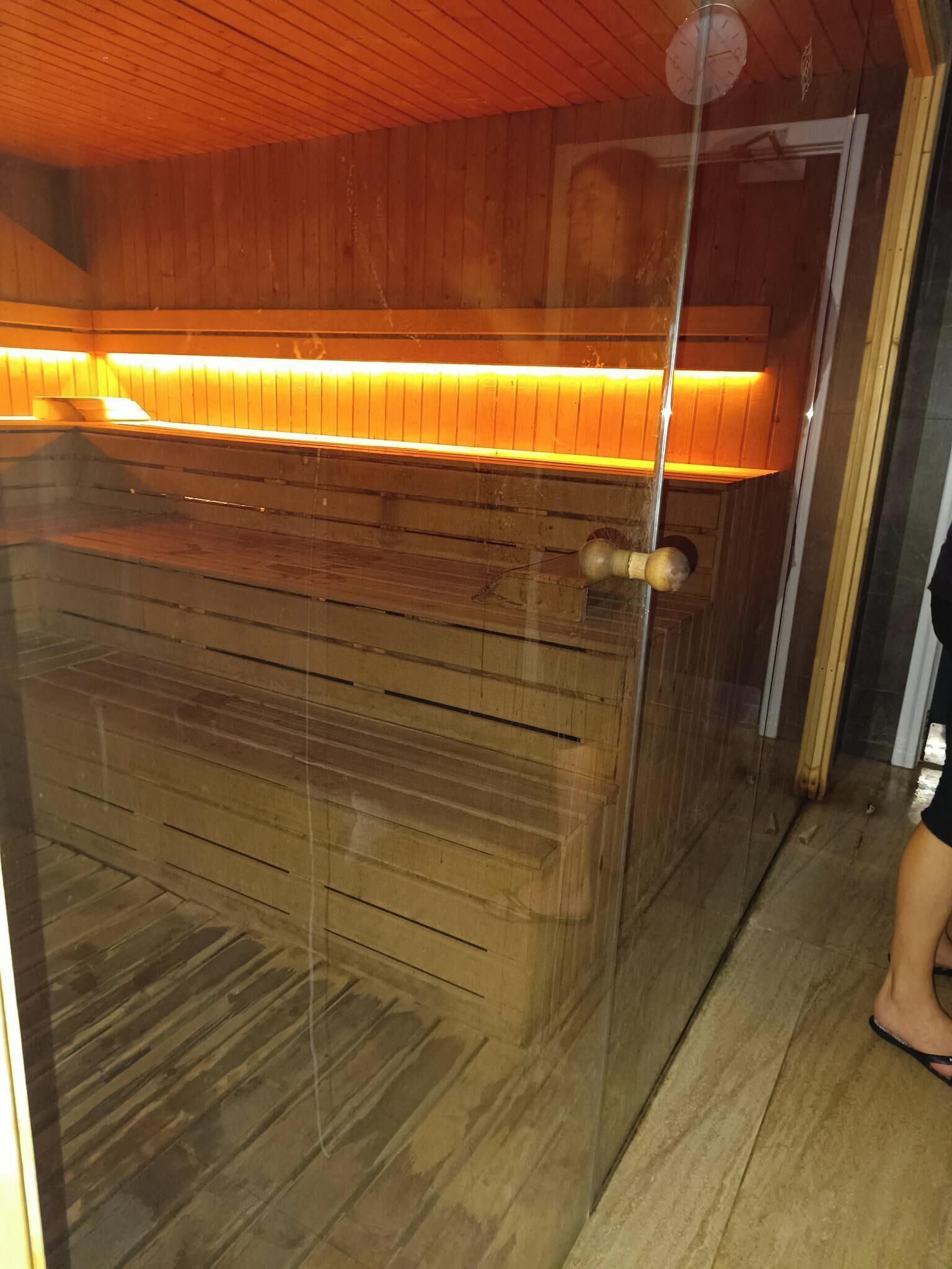 Un interior de madera con un separador de vidrio, una puerta de madera y una lámpara.