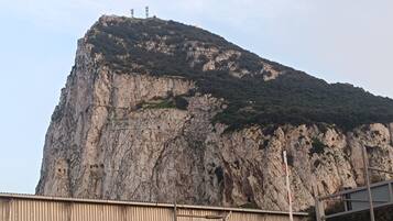 A large, rugged cliff with a metal structure on top.