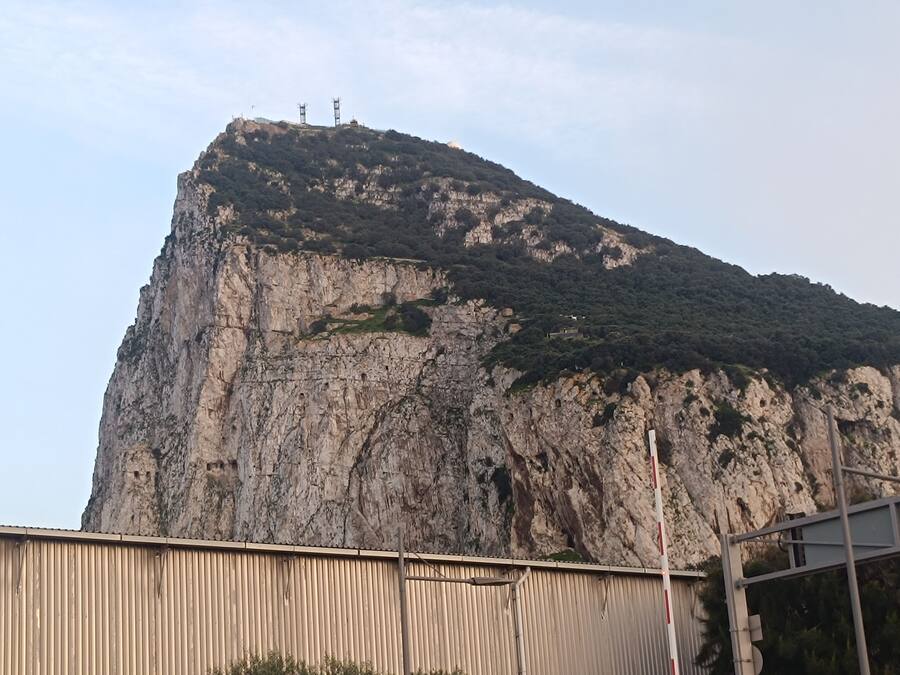 A large, rugged cliff with a metal structure on top.