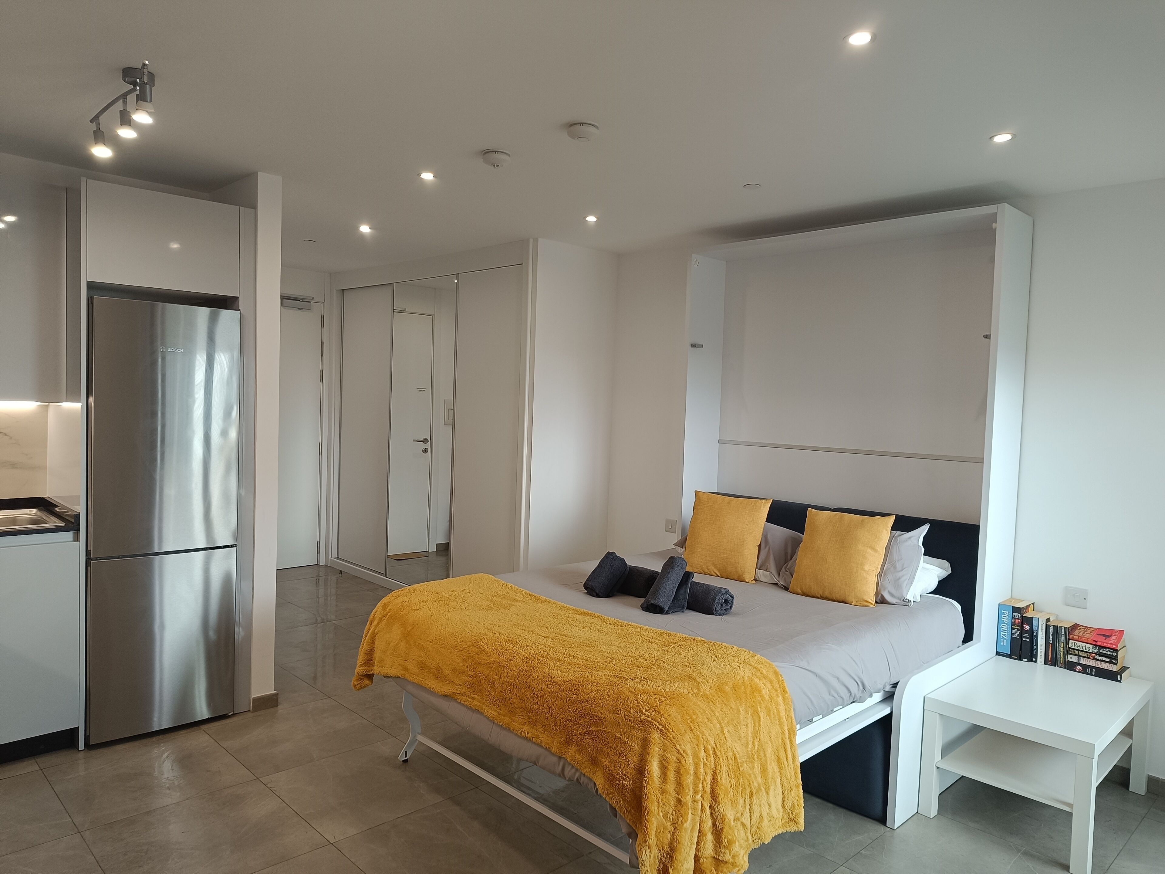 Une chambre moderne avec un lit, une table de chevet et une armoire intégrée.