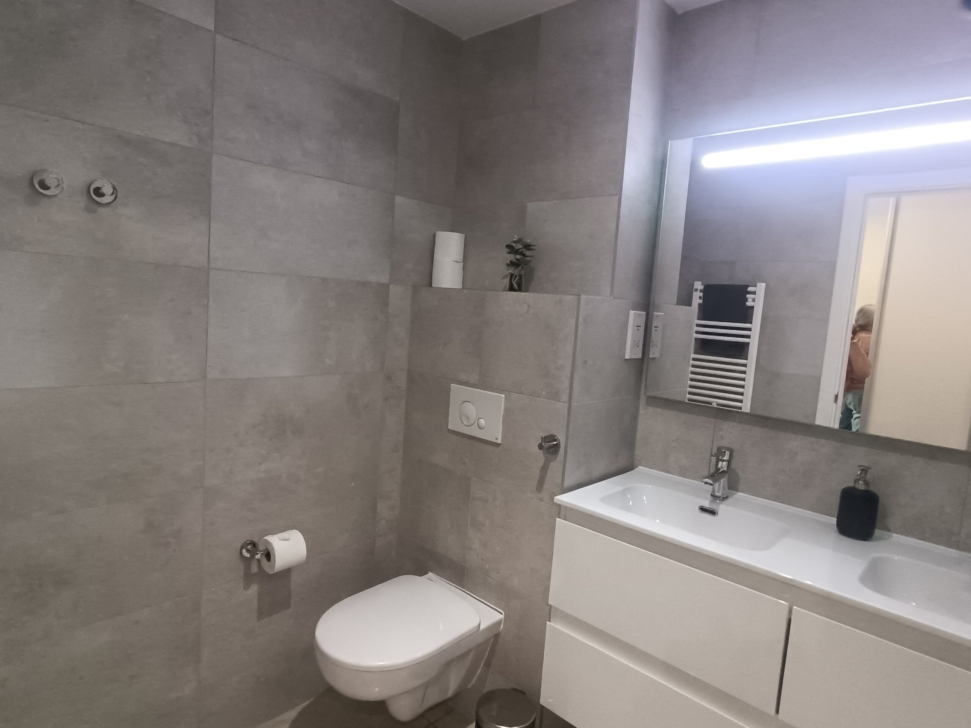 Een moderne badkamer met toilet, wastafel en douche.