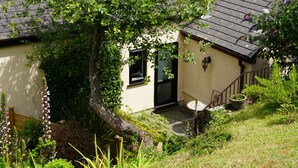 Ένα κτίριο στην ακτή, με έναν πύργο από πέτρα, έναν κήπο με διάφορα φυτά και θέα στη θάλασσα.