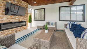 A modern outdoor living area with a stone wall, flat-screen TV, wicker furniture, and a ceiling fan. - Casa Larissa , Grill & Chill Retreat- Heated Pool
3 bedroom Home in Katy TX (Katy)