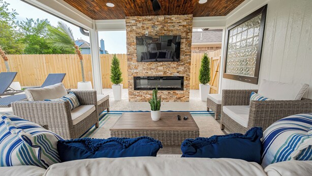 An outdoor living area with wicker furniture, a stone fireplace, and a ceiling fan. - Casa Larissa , Grill & Chill Retreat- Heated Pool
3 bedroom Home in Katy TX (Katy)