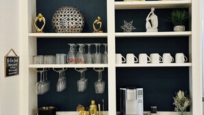 A kitchen with white cabinetry, a black backsplash, and various kitchen items including a coffee machine, wine glasses, and decorative objects. - Casa Larissa , Grill & Chill Retreat- Heated Pool
3 bedroom Home in Katy TX (Katy)