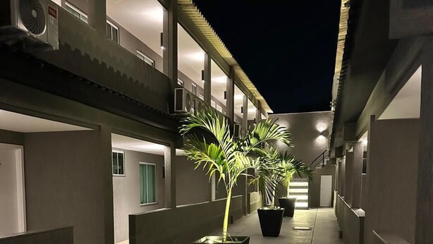 Un pasillo exterior cubierto con plantas en macetas y una escalera que conduce a un nivel superior.
