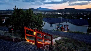 Una casa con una escalera roja y vistas a un pueblo y montañas al fondo.
