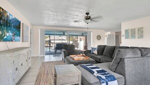 A spacious living room with a grey sofa, a wooden coffee table, and a large painting on the wall.
